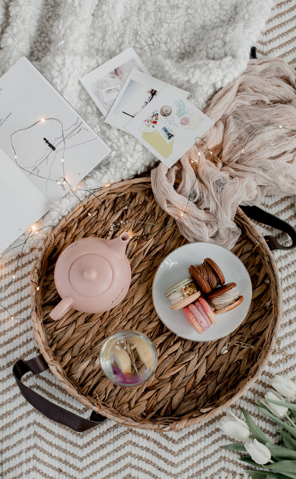 Kintsugi Tea Sweets with you herbal teas will help you boost your mood. Teas with macaroons, a pink tea kettle in a basket with a white plate of four macaroons . Kintsugi Tea Black owned Company.